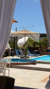 a swimming pool with chairs and an umbrella at Vilarejo Cipó in Serra do Cipo