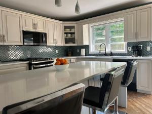 een keuken met witte kasten en een kom sinaasappels op een aanrecht bij Rutledge Lake Retreat in Bancroft