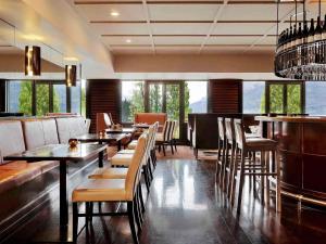 un restaurante con mesas y sillas y un bar en Hotel St Moritz, Queenstown - MGallery Collection, en Queenstown