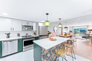 a kitchen with white cabinets and a kitchen island with a table at Cocoa Beach Towers - Oceanfront Resort with Heated Pool, Tennis Steps from the Pier in Cocoa Beach