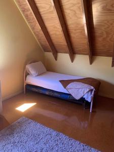 - un petit lit dans une chambre dotée d'un plafond en bois dans l'établissement Hosts on the Coast Titoki Palms, à Matarangi