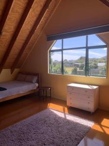 a bedroom with a bed and a large window at Hosts on the Coast Titoki Palms in Matarangi