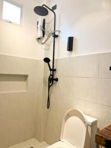 La salle de bains est pourvue d'une douche, de toilettes et d'un pommeau de douche. dans l'établissement Zande Point Apartments, à General Luna