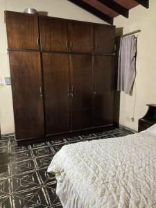 Un dormitorio con una cama y armarios de madera. en Alojamiento a pasos de Asunción, en Fernando de la Mora