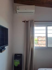 ein Zimmer mit einem Fenster mit einem Fernseher und einem Vorhang in der Unterkunft Septimo Sol in Capilla del Monte