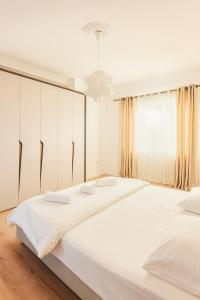 een witte slaapkamer met twee bedden en een raam bij Blloku Luxury 2 bedroom apartment in Tirana