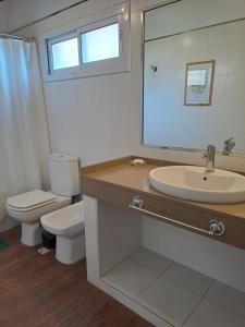 ein Badezimmer mit Toilette, Waschbecken und Spiegel in der Unterkunft Septimo Sol in Capilla del Monte