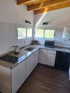 eine Küche mit weißen Schränken und schwarzen Geräten in der Unterkunft Loft en las Sierras in Villa Giardino