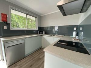 a kitchen with white cabinets and a sink and a window at Atherton Tourist Park in Atherton