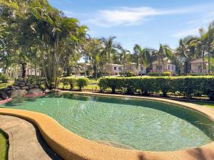 a swimming pool in a yard with palm trees at Atherton Tourist Park in Atherton