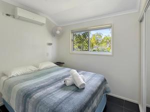 a white bedroom with a bed with a window at Atherton Tourist Park in Atherton
