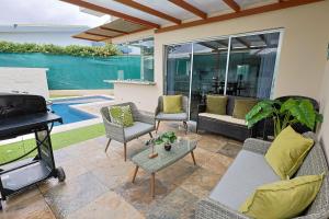 a patio with a couch and chairs and a grill at Casa en puntaleona Condomio Bambu in Quebrada Ganado