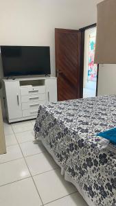 ein Schlafzimmer mit einem Bett und einem Flachbildfernseher in der Unterkunft Maracarib centro - 200m da praia in Maragogi