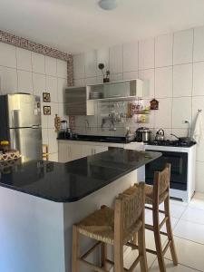 eine Küche mit einer schwarzen Theke und zwei Stühlen in der Unterkunft Maracarib centro - 200m da praia in Maragogi