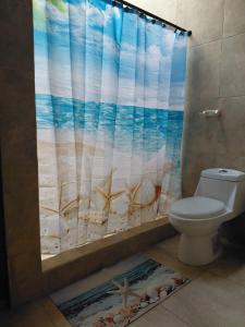 a bathroom with a shower curtain with a toilet at El Remanso Hotel y Restaurante in Rivas