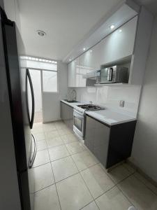 Il comprend une cuisine blanche équipée d'une cuisinière et d'un réfrigérateur. dans l'établissement casa santacruz, à Guadalajara