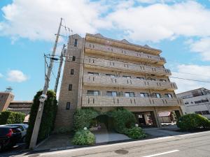 ein großes Backsteingebäude mit Büschen davor in der Unterkunft The Global West in Niihama