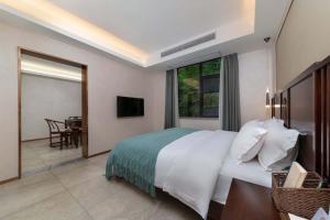 ein Schlafzimmer mit einem Bett und einem Tisch und einem Fernseher in der Unterkunft Snowy&Sunny Resort Phoenix City Hunan in Fenghuang