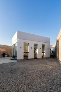 ein weißes Gebäude mit Glastüren an einer Kiesauffahrt in der Unterkunft Casa Viña Sol - Vive la ruta del Vino y del Pisco in Ica