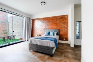 a bedroom with a brick wall and a bed at Casa Viña Sol - Vive la ruta del Vino y del Pisco in Ica