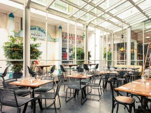 Un restaurante con mesas y sillas frente a un edificio. en Mercure Surabaya Grand Mirama, en Surabaya