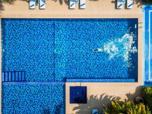 a large blue swimming pool with a surfer in the water at La Veranda Resort Phu Quoc - MGallery in Phu Quoc