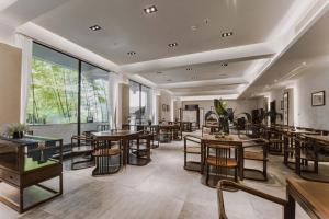 ein Restaurant mit Tischen und Stühlen und Fenstern in der Unterkunft Snowy&Sunny Resort Phoenix City Hunan in Fenghuang