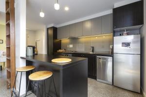eine Küche mit einer Theke mit Hockern und einem Kühlschrank in der Unterkunft Spacious 1-Bed Townhouse in Norlane in Norlane
