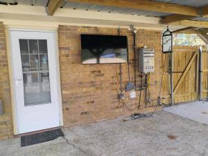 a brick wall with a television and a door at The Denham Springs Esape- Pool, Comfort & Charm in Denham Springs