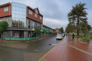 a person walking down a street next to a building at Hotel Plaza Los Leones in Curanilahue