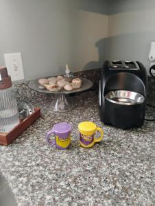 a kitchen counter with two cups and a plate of donuts at The Denham Springs Esape- Pool, Comfort & Charm in Denham Springs