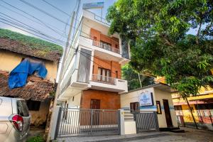 a white building with a balcony and a tree at Infinity Rooms Kazhakkoottam Technopark in Trivandrum