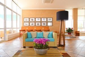 a living room with a blue couch and flowers at Vitória Hotel Express Dom Pedro in Campinas