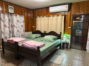 a bedroom with a bed with two pink pillows at อิ๊กขะหลิ๊ก โฮมสเตย์ริมน้ำน่าน in Nan