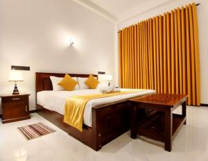 ein Schlafzimmer mit einem Bett und einem Tisch und gelben Vorhängen in der Unterkunft Coco Mount Residence - Hiriketiya in Dikwella