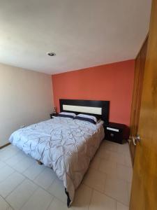 ein Schlafzimmer mit einem Bett mit einer orangefarbenen Wand in der Unterkunft Casa puebla univ Politecnico in Puebla