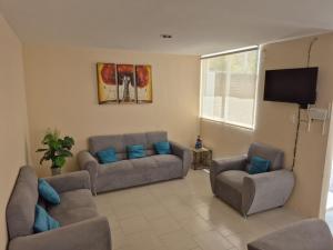 ein Wohnzimmer mit Sofas und einem Flachbildfernseher in der Unterkunft Casa puebla univ Politecnico in Puebla