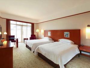 ein Hotelzimmer mit zwei Betten und einem Schreibtisch in der Unterkunft Pullman Zhangjiajie Hotel in Zhangjiajie