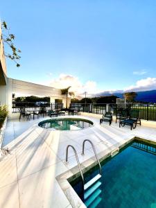a swimming pool on a patio with tables and chairs at NOVIDADE! Apartamento Bella Vita Bertioga in Bertioga