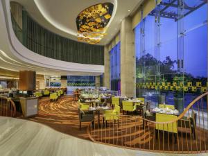 um restaurante com mesas e cadeiras em um prédio em Novotel Ahmedabad em Ahmedabad
