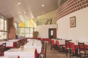 un comedor con mesas blancas y sillas rojas en Hotel Tabarana, en Serra Negra