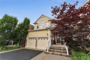 ein gelbes Haus mit Garage und Einfahrt in der Unterkunft Tranquil Haven near Niagara in Thorold