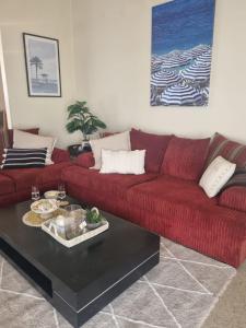 a living room with a red couch and a table at Hosts on the Coast Family Times in Whitianga