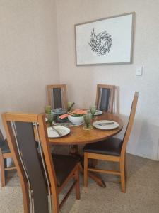 a dining room table with two chairs and a table with plates at Hosts on the Coast Family Times in Whitianga +19 photos