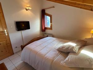 萨莫安斯Confortable T3 au cœur de Samoëns avec WIFI et parking - FR-1-629-152的一间卧室，墙上有一张床和一台电视