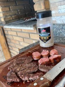 a cutting board with meat and a jar of steak sauce at Vivenda Hotel in Arapiraca