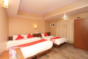 ein Hotelzimmer mit zwei Betten mit roten Kissen in der Unterkunft Hotel Om in Pokhara
