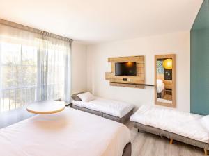 ein Wohnzimmer mit zwei Betten und einem Fernseher in der Unterkunft ibis Styles Marennes d'Oléron in Marennes + 32 Fotos