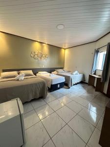 a hotel room with two beds and a window at Pousada Alter Villa Suítes in Alter do Chao