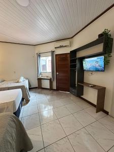 a hotel room with a tv and a bedroom at Pousada Alter Villa Suítes in Alter do Chao